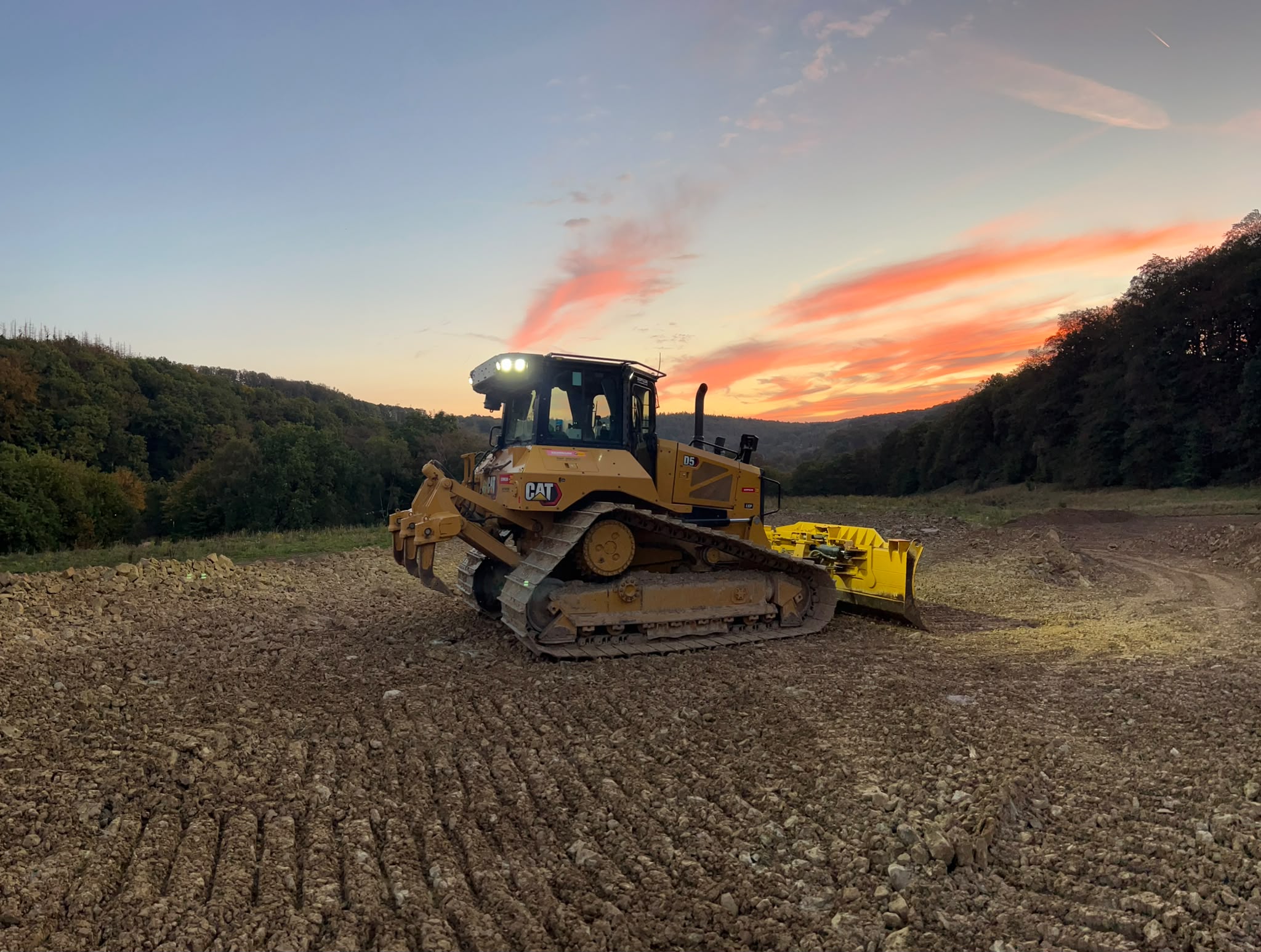 CAT Planierraupe auf einer Baustelle bei Sonnenuntergang